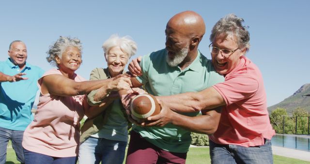 Group of joyful seniors playing American football in a beautiful outdoor setting on a sunny day. This image is ideal for depicting active, healthy lifestyles among older adults, promoting outdoor activities and senior fitness programs, and visually representing concepts of teamwork, fun, and friendship during retirement.