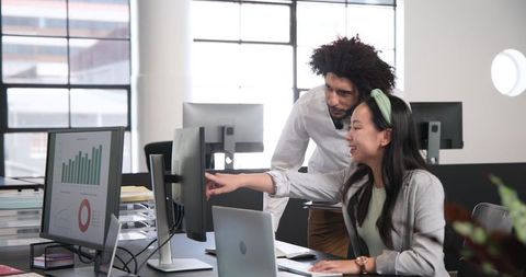 Collaborative team analyzing data on office computer screens
