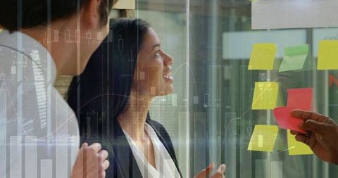 Team brainstorming using colorful sticky notes on glass wall with data overlays and charts