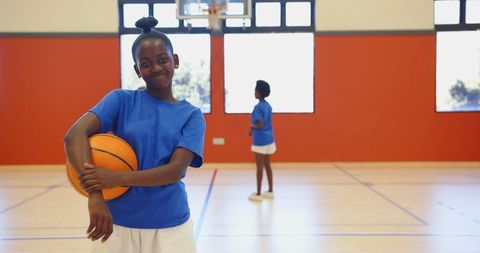 Young african american girls holding basketball inside gymnasium