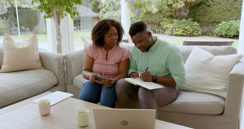 Mature couple managing finances at home with laptop and notes