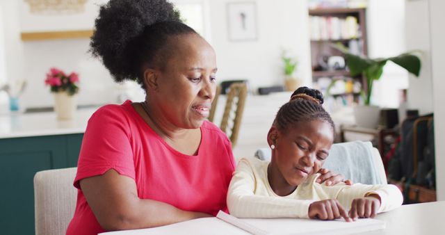 Image of smiling african american grandmother listening to her granddaughter reading braille. Sight disability, communication, blindness, family and domestic life.