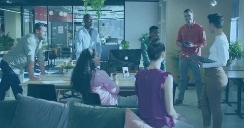 Team sharing ideas in modern workspace around wooden table
