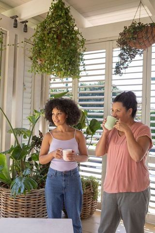 Mother and Daughter Relaxing with Morning Coffee on Cozy Porch