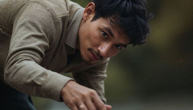 Leaning Asian man reaching forward looking intently in park closeup portrait with ring