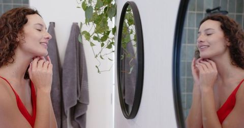 Woman Practicing Self-Care in Modern Bathroom with Mirror Reflection