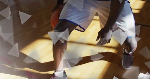 Athlete dribbling basketball in gym with dynamic triangular overlays
