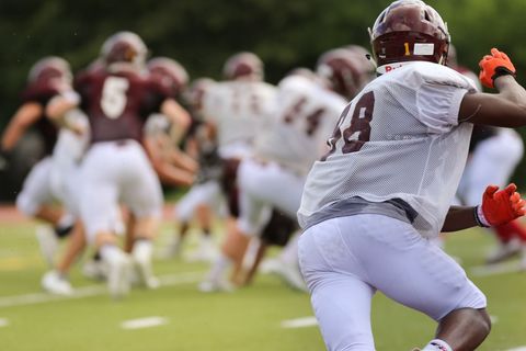 Sprinting football player wearing no. 48 mesh jersey during team practice drill on turf