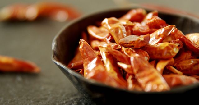 A bowl of dried red chilies on a dark surface signifies global culinary spice and flavor. - Download Free Stock Photos Pikwizard.com