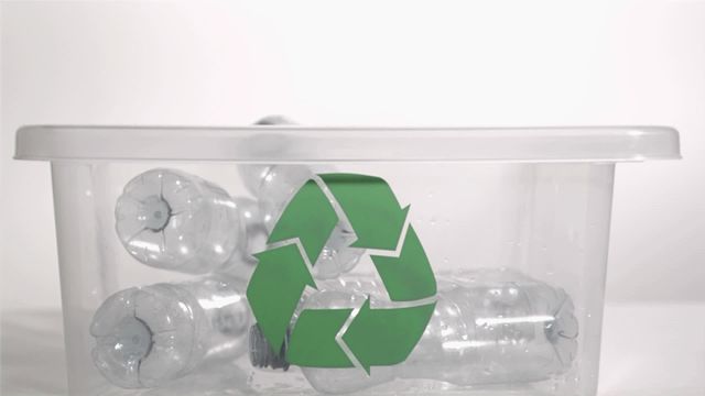 Plastic bottles falling in super slow motion into a recycle bin against a white background