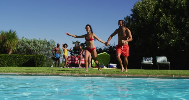 Diverse group of friends having fun jumping into a swimming pool. hanging out and relaxing outdoors in summer.