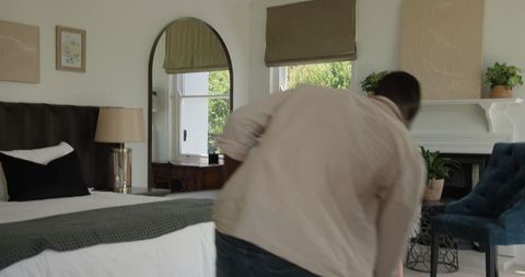 Man tidying modern bedroom interior design decorated with elegant detail