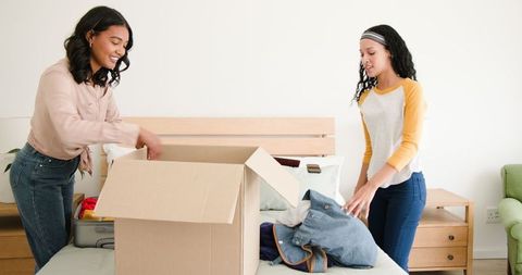 Mother and Daughter Packing for Family Trip in Bedroom