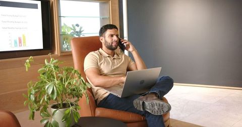 Man Multitasking with Laptop and Smartphone in Modern Office