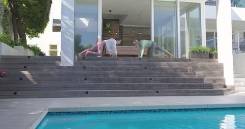 Poolside fitness routine: two women exercising on wooden steps, stretching and doing core work