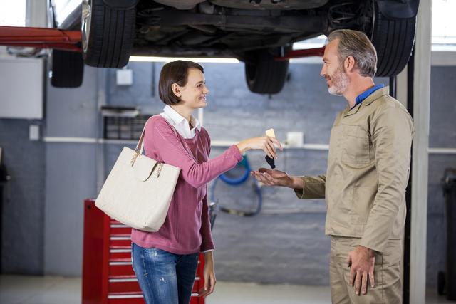Customer giving her car keys to mechanic at the repair garage