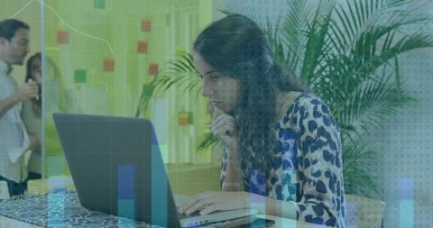 Focused woman working on laptop with data overlay in modern coworking space, analytics teamwork