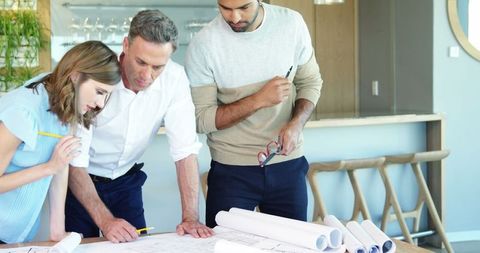 Team Collaborating on Architectural Blueprint in Modern Office - Download Free Stock Images Pikwizard.com