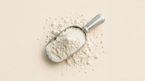 Metal scoop with milk powder on beige surface for baking concepts