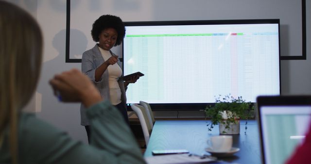 African american woman with digital tablet giving a presentation to her office colleagues at office. business, professionalism and office concept