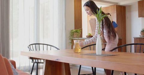 Young Woman Setting Dining Table in Modern Bright Home