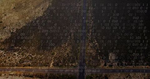 Aerial view of desert roads with binary code overlay