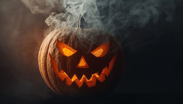 Spooky carved jack-o'-lantern with rising smoke in dark