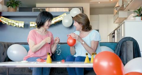 Senior Female Friends Preparing for Birthday Celebration with Balloons