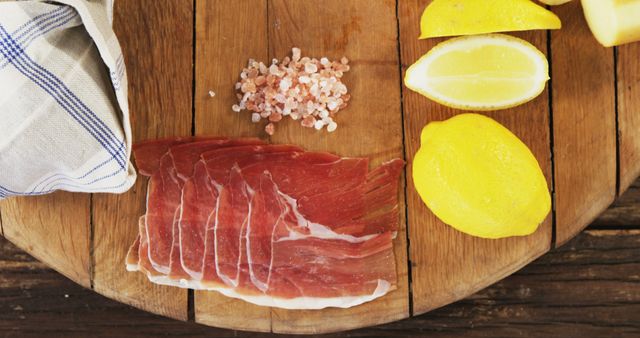 Sliced Prosciutto with Pink Salt and Lemon Wedges on Wooden Board - Download Free Stock Photos Pikwizard.com