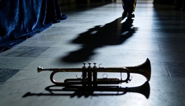 Brass trumpet lying on marble floor casting dramatic shadow with ceremonial uniform velvet