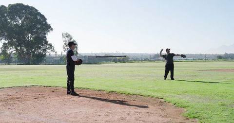 Mature players practicing pitching and catching on sunny baseball diamond