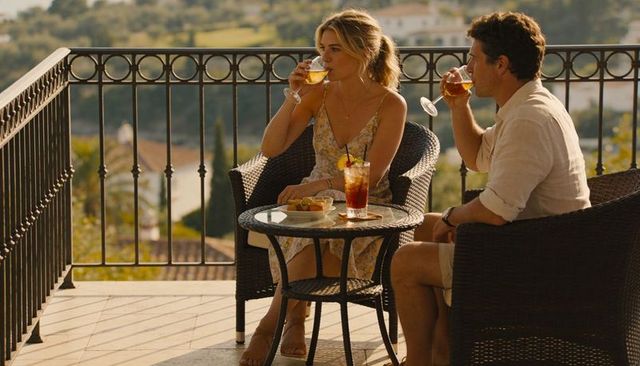 Romantic couple enjoying cocktails on sunlit terrace during golden hour