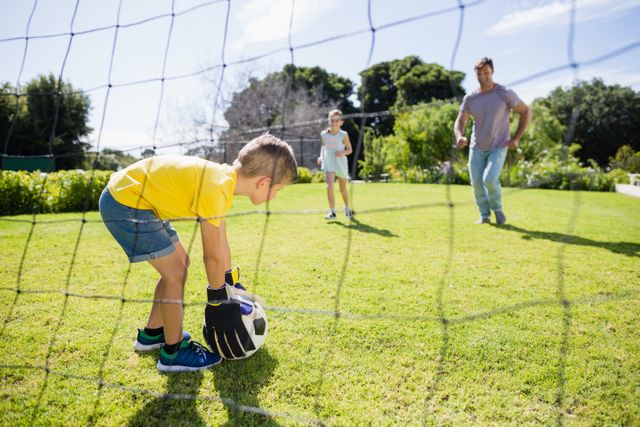 Family enjoying a fun football game in a park on a sunny day. Ideal for promoting family bonding, outdoor activities, and healthy lifestyles. Perfect for use in advertisements, brochures, and websites related to family recreation, sports, and outdoor events.