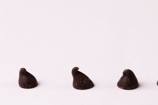 Close-up of chocolate chips on white background, copy space. unaltered, sweet food, studio shot and indulgence.
