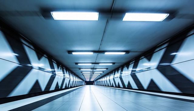 Futuristic subway corridor with chevron walls leading perspective and cool blue lighting
