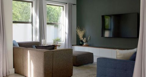 Minimal modern living room with brown sectional, slate accent wall and wall-mounted tv