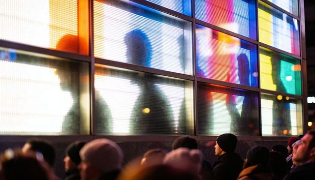 Nighttime crowd watching colorful led wall with blurred silhouettes urban nightlife