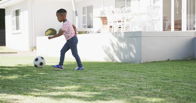 Young child enjoying outdoor activity playing soccer in a backyard on a sunny day. Suitable for topics related to family lifestyle, outdoor activities, childhood fun, and sports.