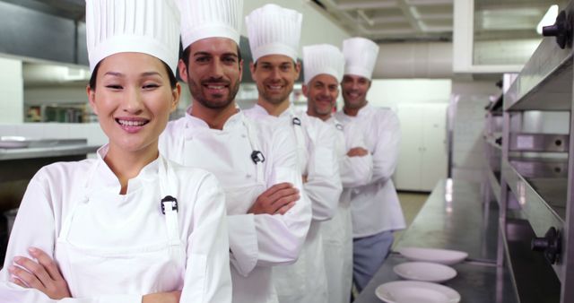 Group of professional chefs standing confidently in a modern industrial kitchen, showcasing unity and teamwork. Ideal for content related to culinary arts, professional cooking, restaurant management, and hospitality promotions. Could be used in banners, brochures, or ads for culinary schools, restaurants, and food industry services.