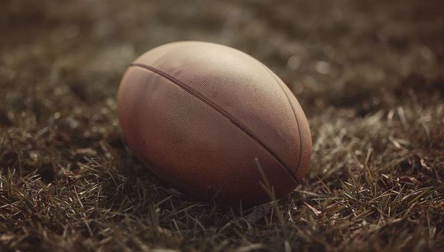 Vintage Leather American Football on Dry Grassy Field