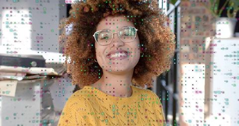 Smiling woman wearing clear glasses and yellow sweater in studio with digital dot overlay