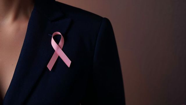 Woman wearing pink ribbon on elegantly tailored navy blazer