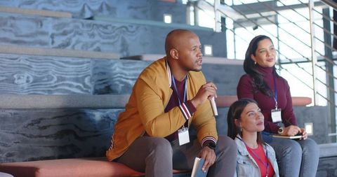 Diverse professionals engaging in conference discussion holding microphone and notebooks