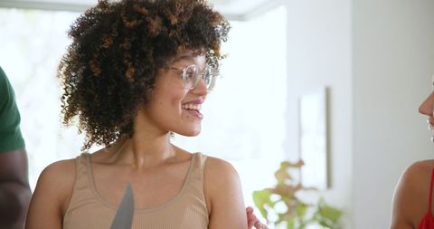 Cheerful friends collaboratively cooking in bright kitchen