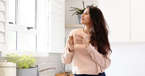 Relaxed Woman Enjoys Morning Coffee in Bright Kitchen