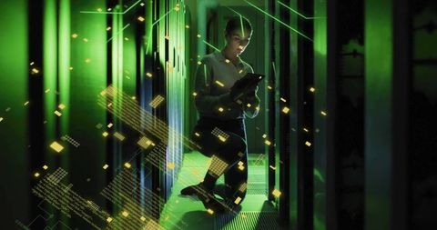Kneeling it technician monitoring servers with tablet holographic data and green glow