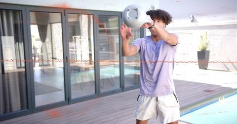 Man swinging kettlebell poolside during outdoor fitness workout on modern deck