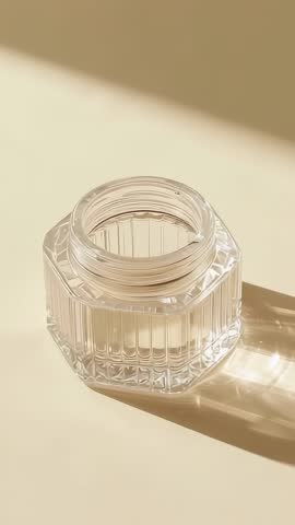 Vertical video: Glass jar refracting sunlight on cream tabletop, casting geometric shadows