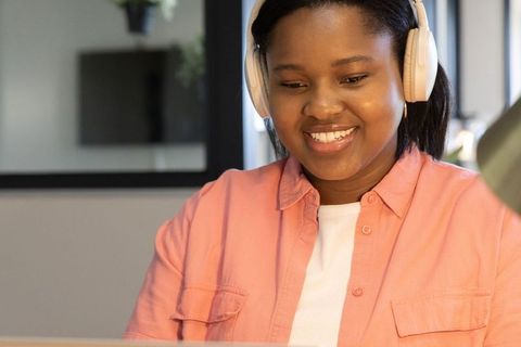 Smiling african american teen studying remotely with headphones and laptop at home desk