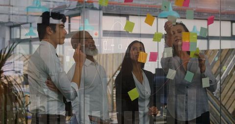 Business team collaborating with colorful sticky notes on glass for strategic planning